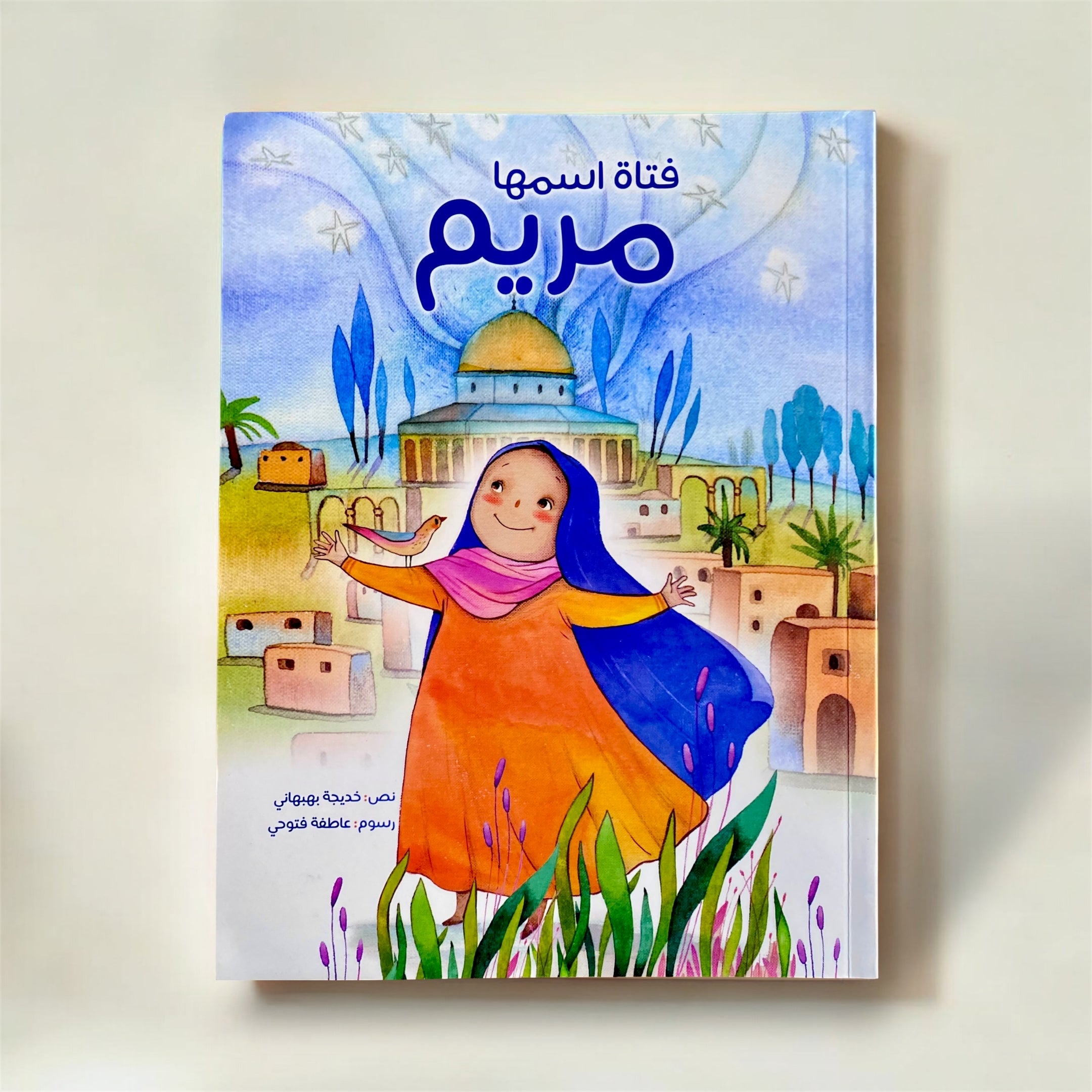 Book cover with a colorful illustration of a girl in a blue headscarf and orange dress, set against a scenic background.