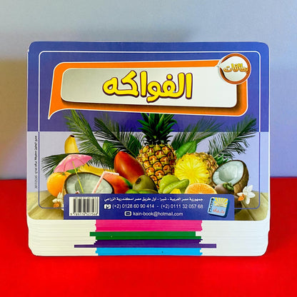 Stack of colorful books with fruit illustrations on a red surface