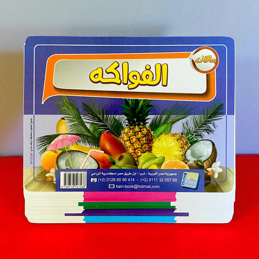 Stack of colorful books with fruit illustrations on a red surface